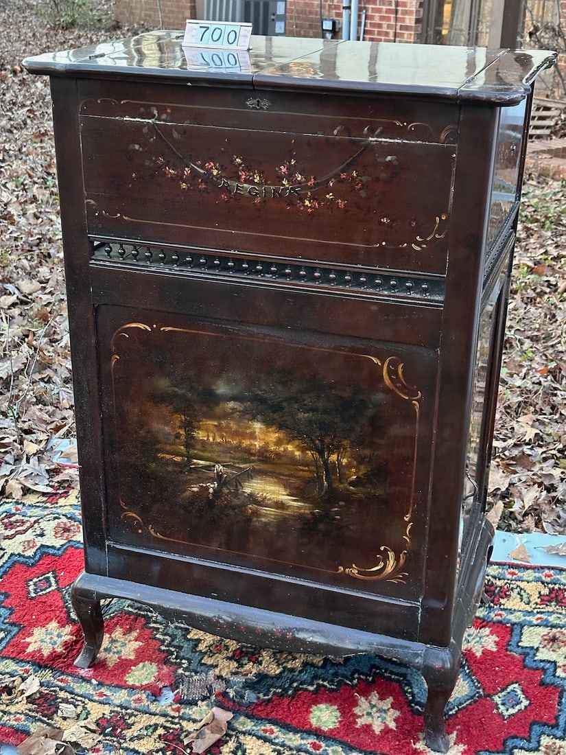 A fantastic Regina Rookwood Decorated Music Box: 20-3/4" disc. One presently with machine. The unit is similar to a casket model phonograph with the top lids are lifted the front and back automatically angles to accommodate the larger 20-3/4" disc. 