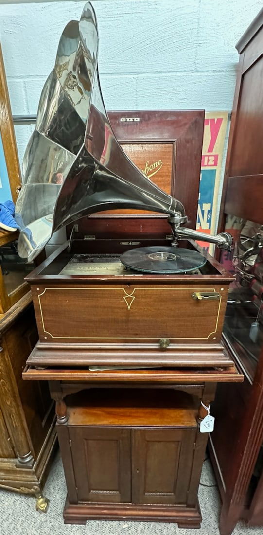 Reginaphone Disc Music Box and Phonograph: Mahogany cabinet. 15.5" machine. Complete with turntable, nickel horn, tonearm and reproducer. Has crank. No broken teeth. Single Comb. Has a mahogany disc cabinet.