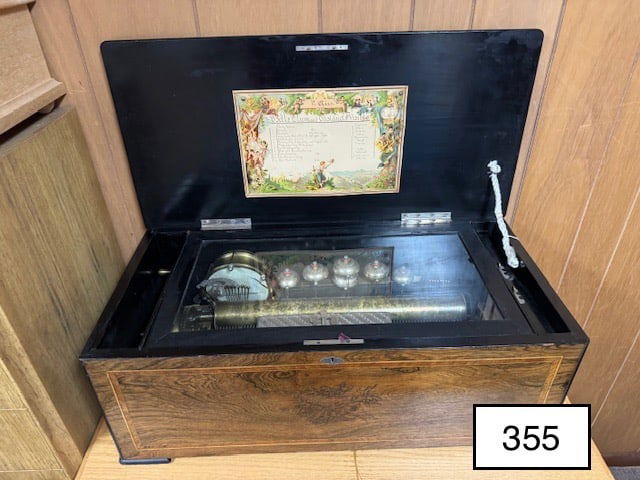 Orchestra 17.5" Cylinder Music Box: Plays 12 tunes with bells drum and Castanet. The case measures 29 inches long by 14 inches deep by 11 inches tall. The drum bells cast and music box plays well. The drum skin is split or cracked.