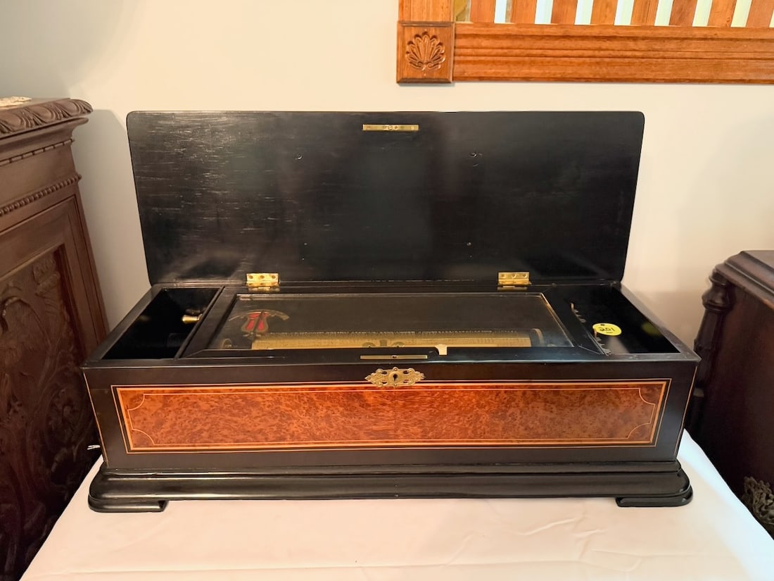 Antique Cylinder Music Box: 10 tune box with tune indicator. The cylinder measures 13". The inlaid case measures 25"x7" high and 10" deep with handles. Good comb with no broken teeth