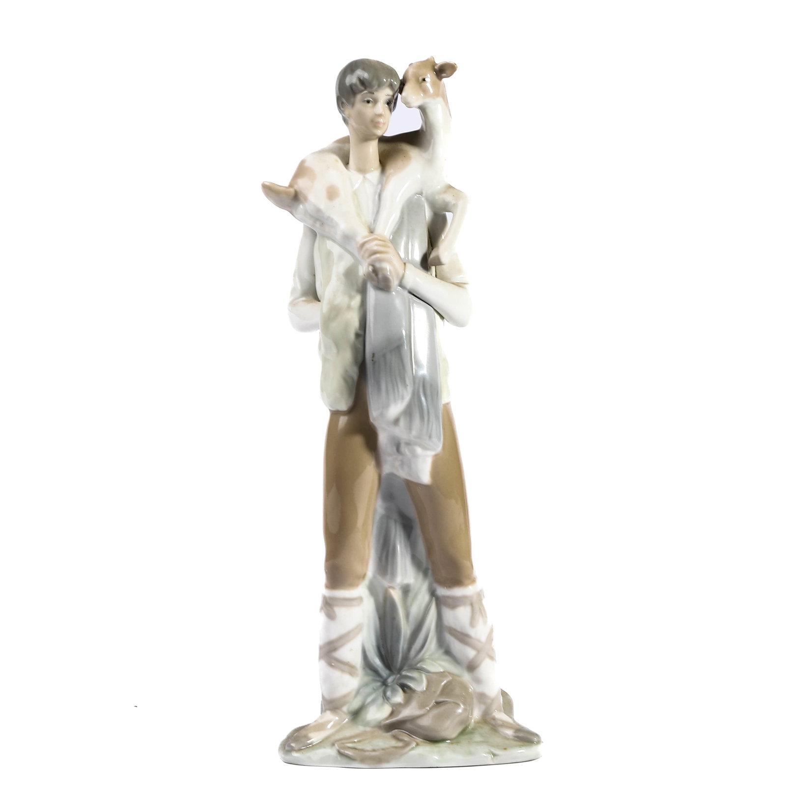 A LLADRÓ PORCELAIN FIGURE OF A SHEPHERD WITH LAMB: Height Height: 10 13/16 in (27.5 cm) Modelled as a young shepherd standing with a lamb draped across his shoulders, dressed in rustic attire and raised on a naturalistic base. Glazed in soft pastel