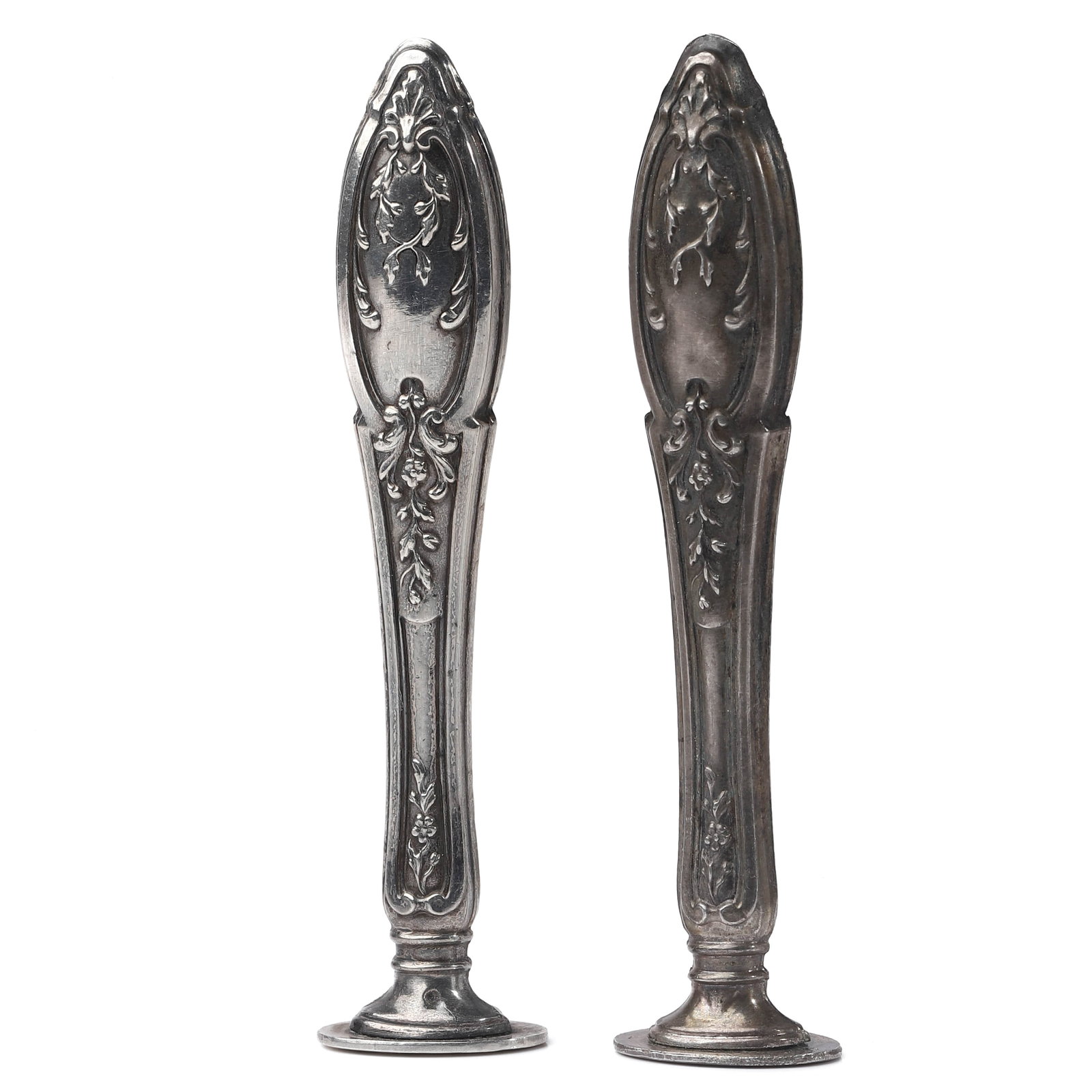 PAIR OF ANTIQUE METAL WAX SEAL HANDLES: Dimensions: Height: 3 7/16 in (8.7 cm) Total Weight: 24.3 g These two antique metal wax seal handles feature an elegant elongated form enriched with finely cast floral and foliate reliefs in a