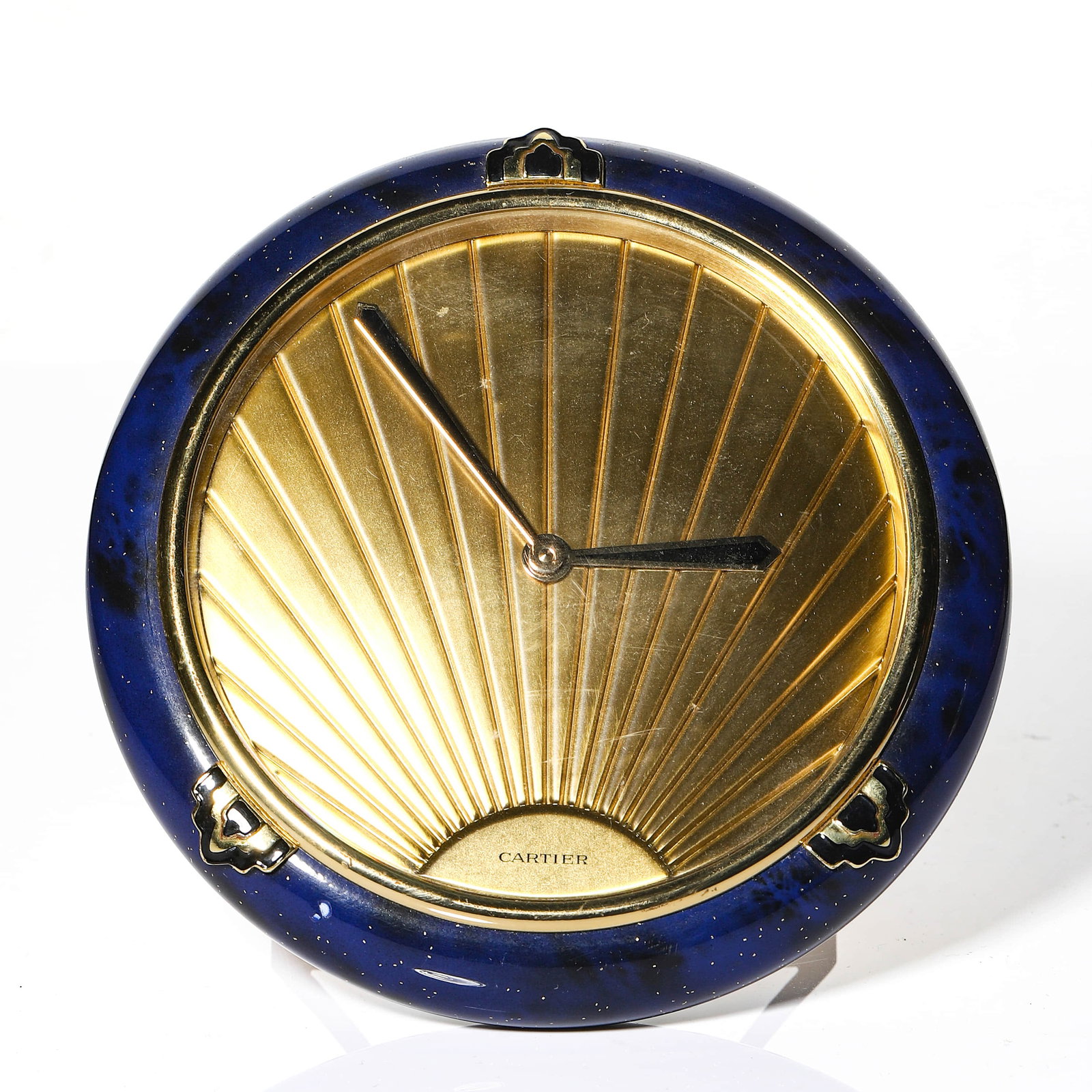 CARTIER QUARTZ DESK CLOCK: Dimensions Diameter: 5 1/8 in (13 cm) Description This Cartier quartz desk clock features a circular gilt metal body with a radiating sunburst-patterned dial, creating a strong sense of depth and