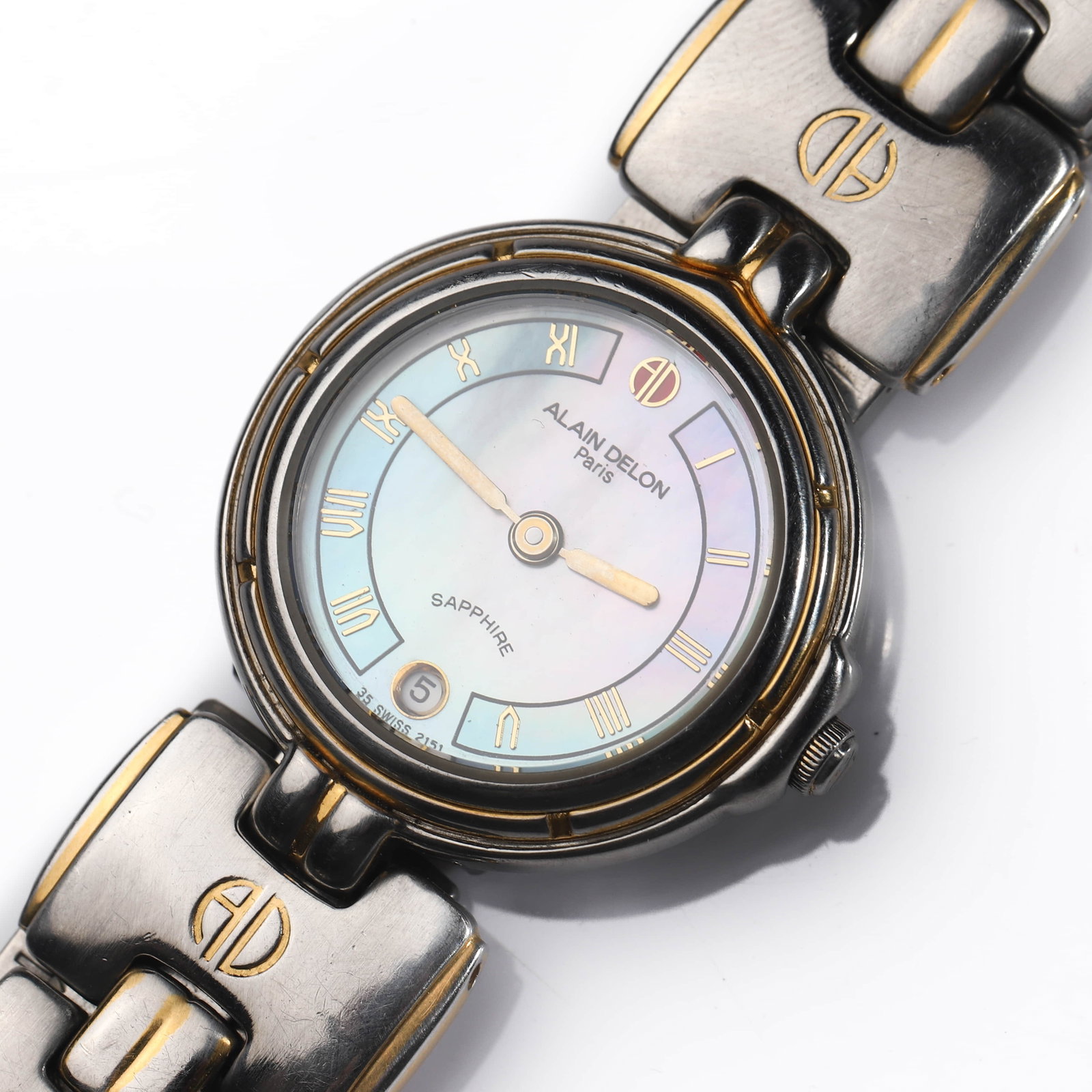 ALAIN DELON PARIS STAINLESS STEEL WRISTWATCH: Dimensions Overall length approx. 7 11/16 in (19.5 cm). Dial diameter: 1 in (25.5 mm). Description This Alain Delon Paris wristwatch features a round stainless steel case fitted with an iridescent