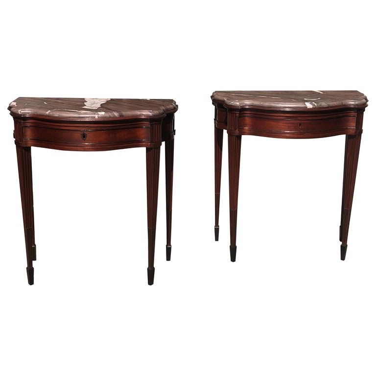 Pair of Late 18th Century Mahogany and Marble English Console Tables: Elegant pair of mahogany neoclassical consoles with marble tops. These Classic consoles are a solid mahogany with a single-drawer. Each console has fluted mahogany legs going down to ebony stop flutin