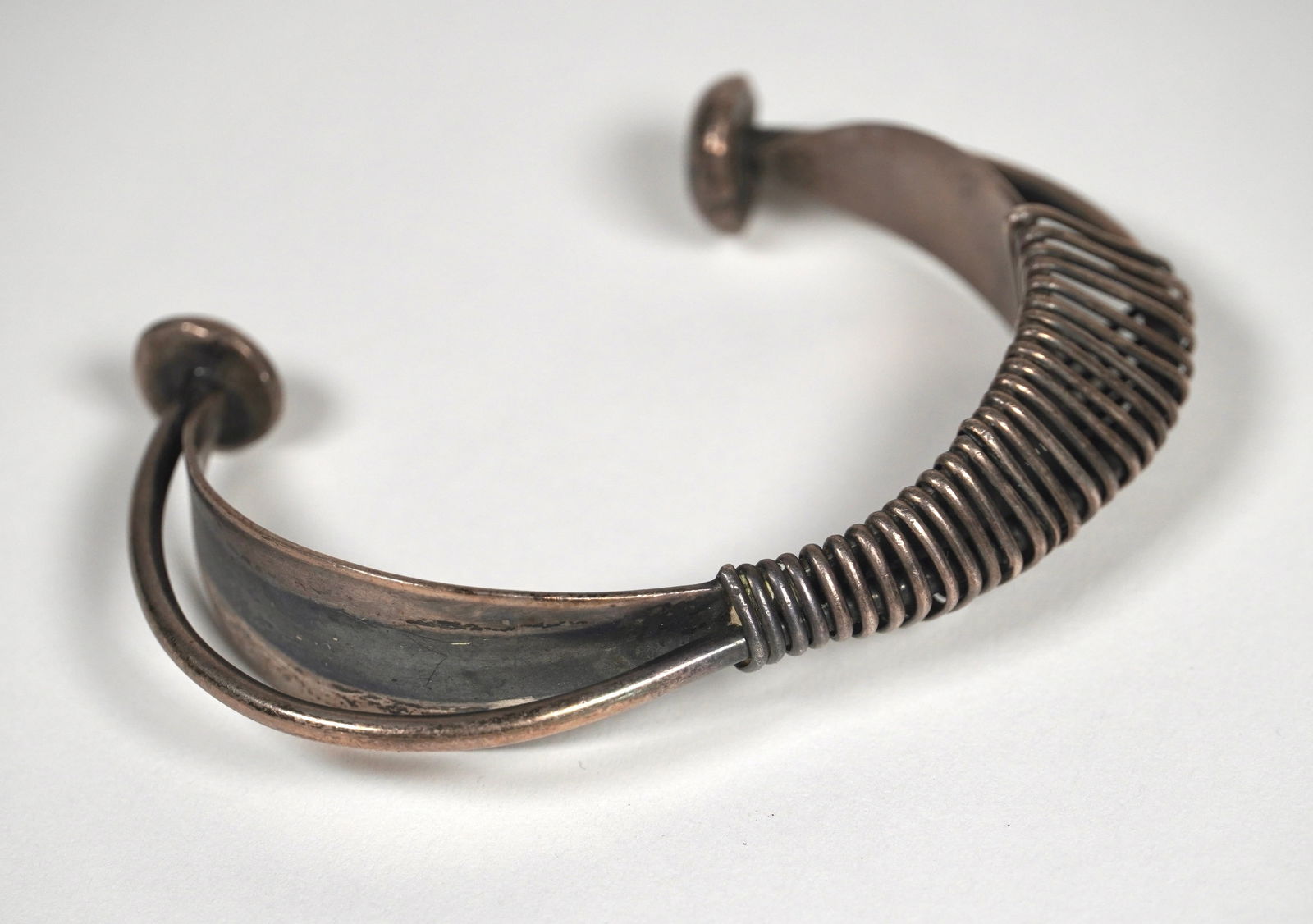 American Modernist Jewelry Maker Ed Wiener (1918-1991) Sterling Bracelet: Sterling sliver modernist bracelet circa 1950s, band with wire embellishments and rounded accents on the ends, 3" W x 2" H x .75" D.