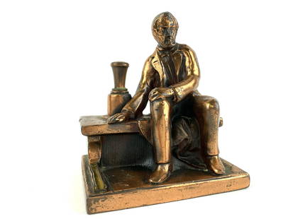 Vintage Ronson Abraham Lincoln Striker Lighter: Copper plated pot metal striker lighter by Ronson. Sculpture depicts Abraham Lincoln sitting on a ledge. Measures 4 5/8" x 4" x 3"