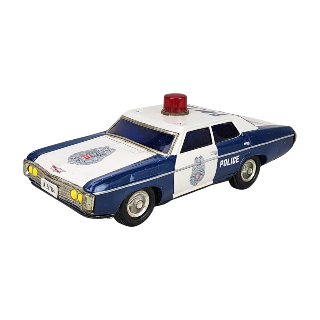 Vintage Tin Toy Chevy Police Car – Made in Japan: Vintage tin toy Chevy police car in white and blue with red roof-mounted siren. Marked "Made in Japan" on the underside. Battery-operated (untested) with rubber tires. Measures 4 1/4" x 11 1/8" x 4 3/