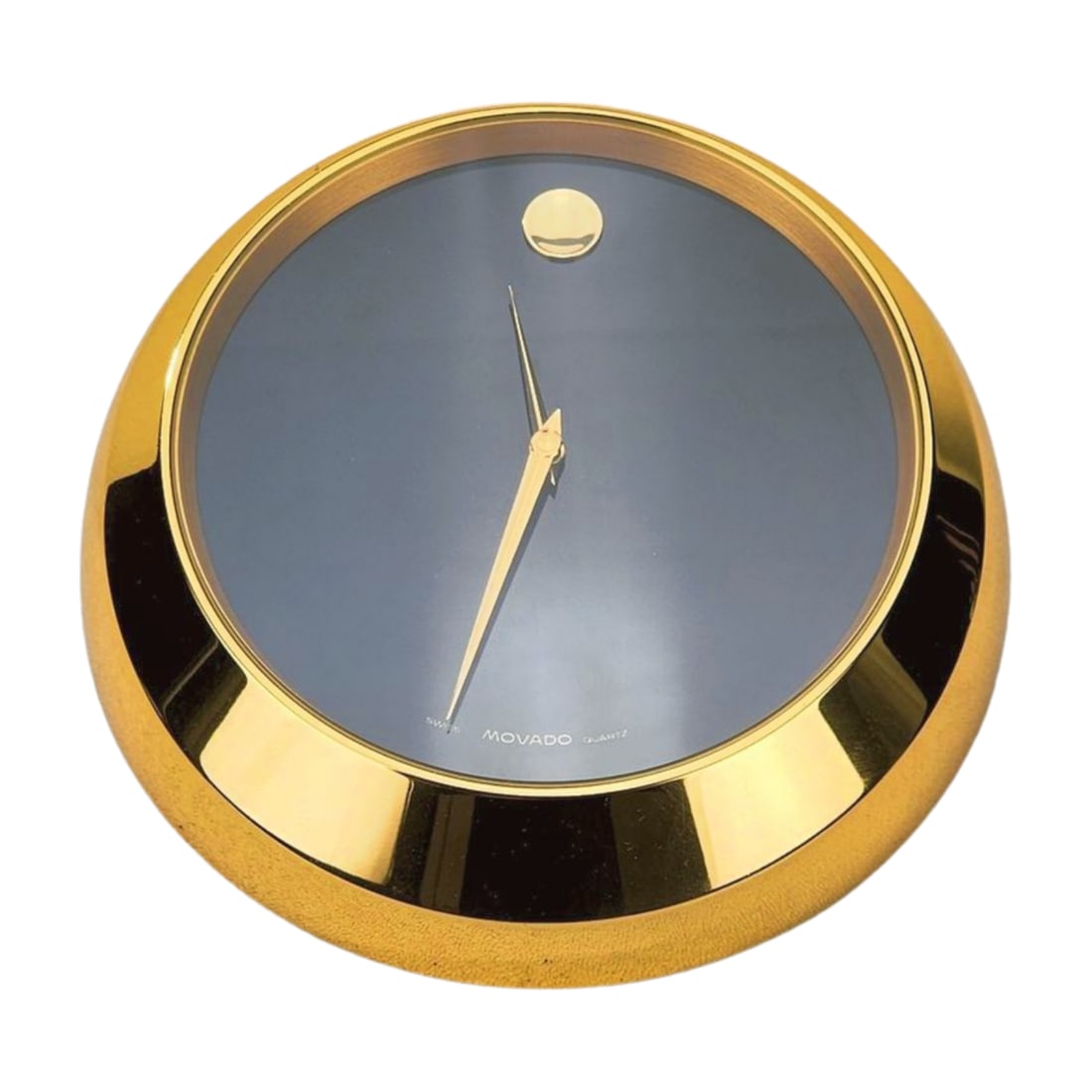 Movado Watch Brand Brass Desk Clock: Heavy brass desk clock by Movado watches. The Movado Museum desk clock sits on an angle with black dial and swiss quartz movement. Measures 5 7/8" x 3 1/4".