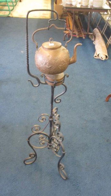 Copper Tea Kettle on Stand: Copper kettle is handmade and incised. Sitting on a wrought iron stand it measures 46"H and is in good condition.