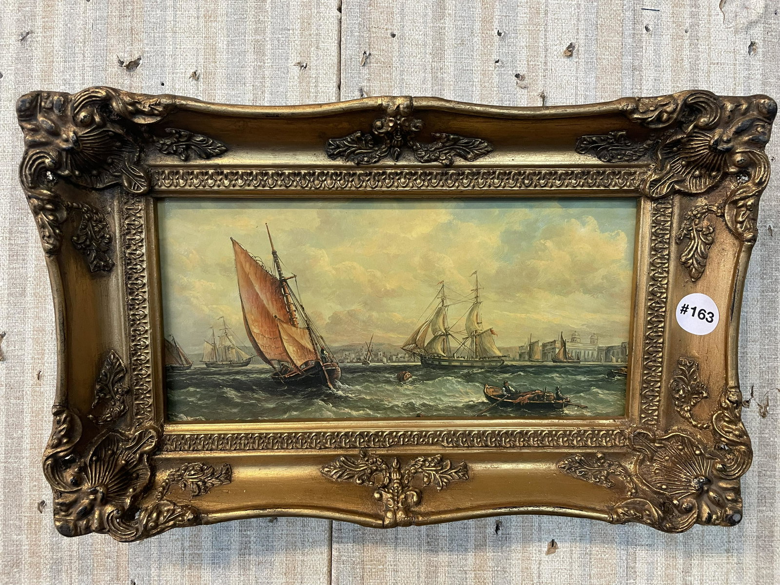 Unsigned Harbor Scene on Board: in fancy gilt frame, depicts sail ships and other in the harbor with a city scape behind. Frame 16"x11"./