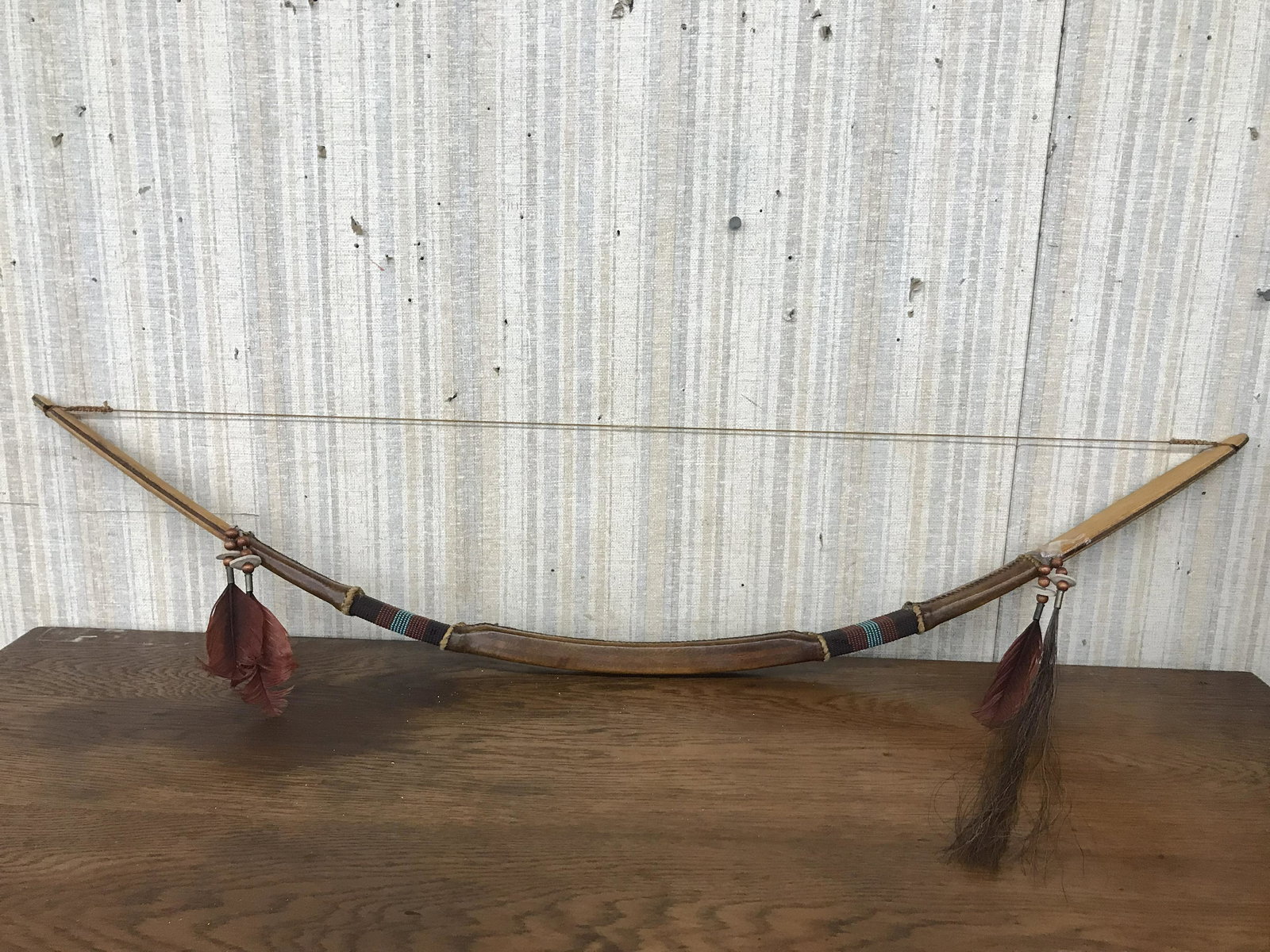 Vintage Native American Bow: Decorated with feathers & beads and leather handle. Measures 43" L x 9" W.