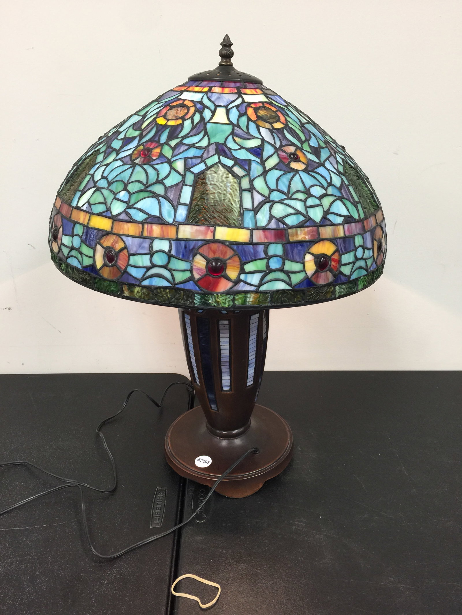 Tiffany Style Lamp: bronze iron base with mosaic style inserts, base lights up with a jeweled shade. 25"H.