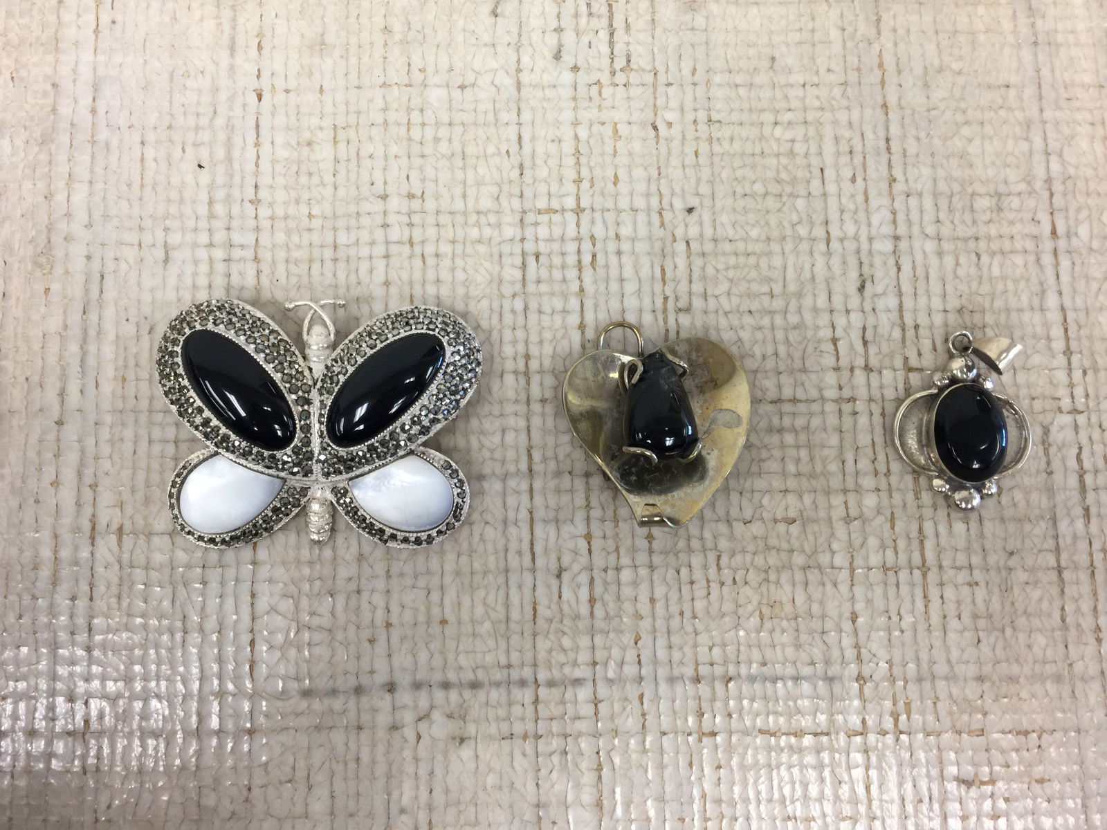 Sterling Jewelry Grouping: Includes 2 sterling & onyx pendants & a sterling butterfly brooch. 1.868 ozt