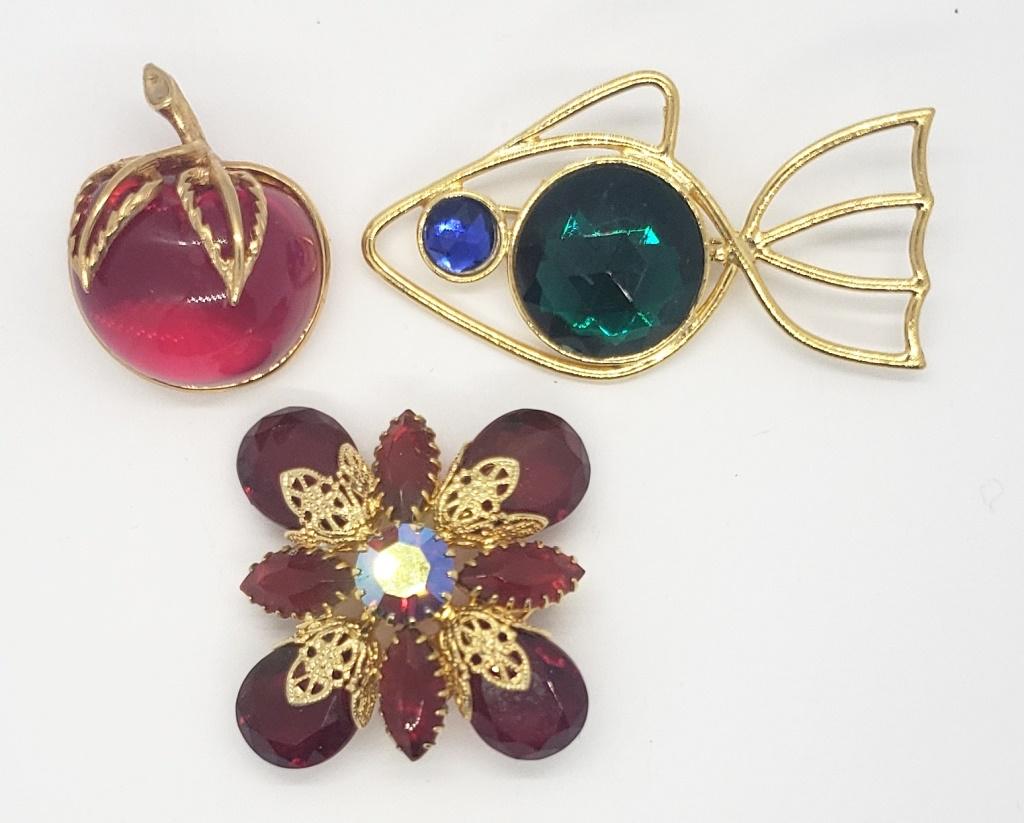 3-VINTAGE GOLD TONED BROOCHES: (1)SARAH: COVENTRY APPLES WITH RED GLASS-LIKE CENTER (1)FISH WITH GREEN AND BLUE RHINESTONES & (1)SQUARE FLORAL DESIGN WITH DEEP REP RHINESTONE ACCENTS