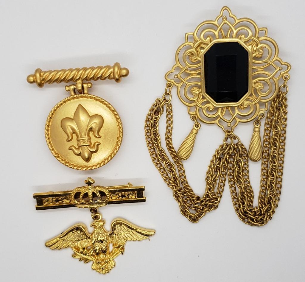 3-VINTAGE GOLD TONED BROOCHES WITH CHARMS: (1)WITH LARGE BLACK RHINESTONE (1)MARKED AK CELTIC LOCKET CHARM & (1)WITH EAGLE CHARM