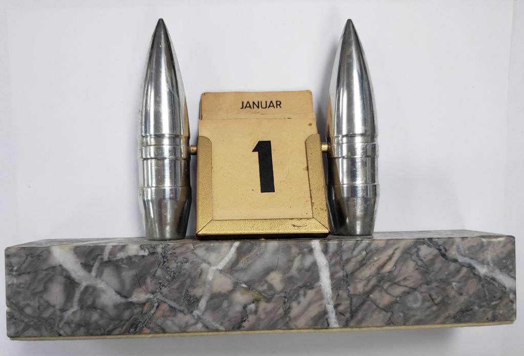 WWII German Military Desk Calander Complete Date: Has 2 coated projectiles holding the Date/Day/Month holder. There is a little note on the back reads "Taken from the desk of a Nazi General in Rothenburg". No other information was given at time of pu