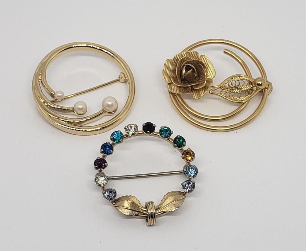 3-VINTAGE GOLD TONED CIRCULAR BROOCHES: (1)MONET WITH FAUX PEARLS (1)WITH RHINESTONES (1)ROSE WITH FILIGREE LEAF