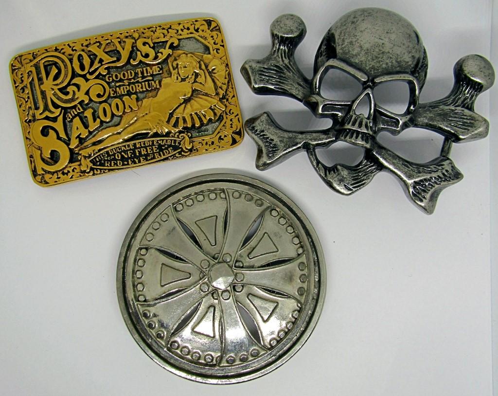 3 VINTAGE BELT BUCKLES;: ROXY'S "GOOD TIME EMPORIUM AND SALOON"; SKULL AND CROSSBONES; SPINNING TIRE RIM WHEEL SILVER STAR "THE ORIGINATOR, NOT THE IMITATION";
