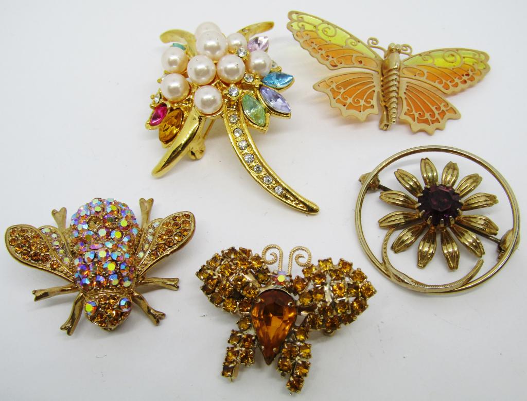 JEWELED GOLD TONE BROOCH LOT: 1-BUTTERFLY W/ GREEN & ORANGE WINGS 1-FLOWER W/ SINGULAR PURPLE STONE 1-BUTTERFLY W/ CITRINE COLORED GEMS 1-MUTLI COLORED GEMS, RHINESTONES & FAUX PEARLS 1-BEE W/ CITRINE & PEARLESCENT GEMS