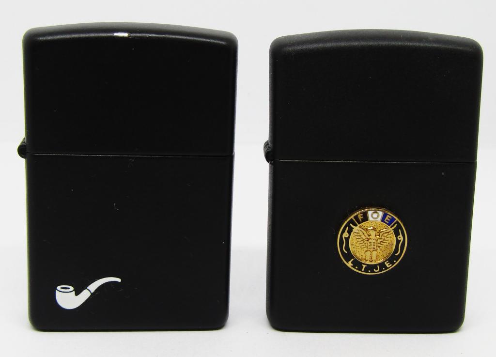 (2) BLACK MATTE ZIPPO LIGHTERS!: ONE HAS WHITE PIPE ON CORNER, 2002; ONE HAS GOLD TONED PENDENT ON FRONT " F.O.E.-L.T.J.E"