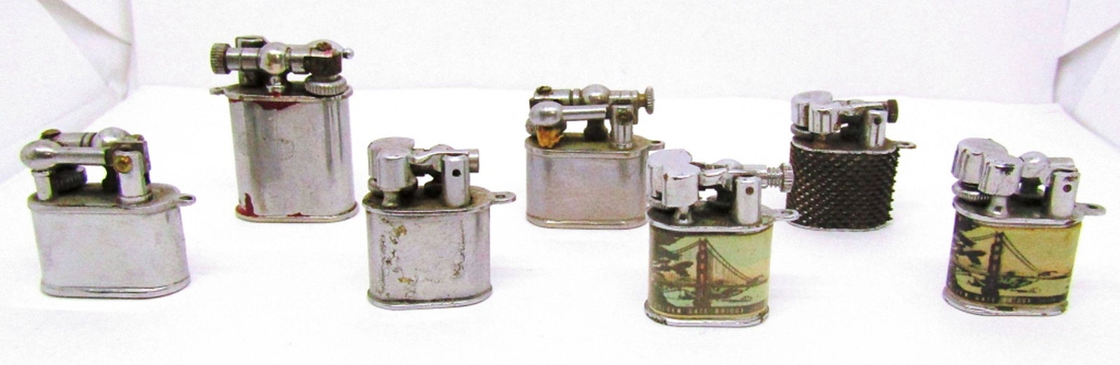 (7) VINTAGE MINI LIFT ARM LIGHTERS!: 2 "APOLLO" , ONE "PERKY" , ONE CHAIN FEEL OUTSIDE, ONE RED CHIPS , 2 "GOLDEN GATE BRIDGE AND SEAL ROCKS!