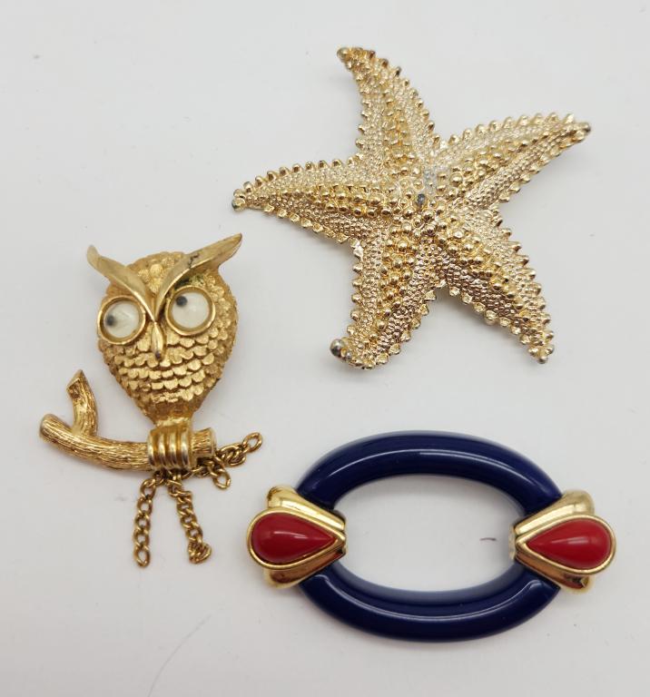 (3)VINTAGE GOLD TONED BROOCHES: (1)AVON OWL: WITH GOOGLY EYES (1)STARFISH (1)WITH NAVY BLUE AND RED LUCITE