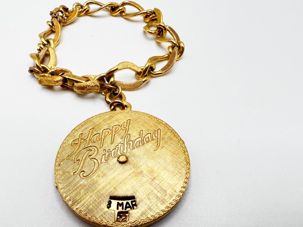 MONET BIRTHDAY BRACELET: MONET BIRTHDAY BRACELET , INTERCHANGEABLE MONTHS AND DATES THAT TURN INSIDE, ON A GOLD TONE MONET BRACELET