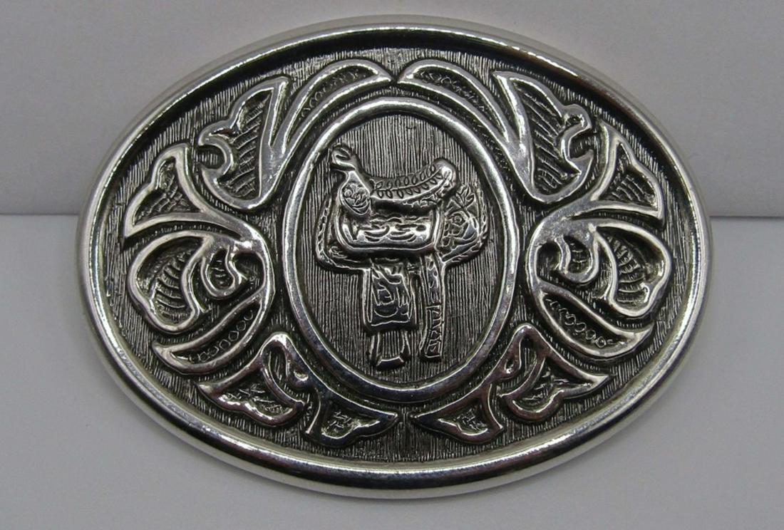 AVON BELT BUCKLE W/A SADDLE ENGARVED: A SADDLE DESIGN IN THE MIDDLE WITH A DESIGN AROUND IT,3IN IN LENGTH
