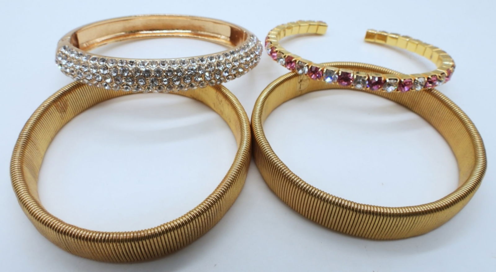 (4) GOLD TONE BRACELETS: 2- ALL GOLD TONE STRETCHY, 1- HINGED BRACELET WITH WHITE RHINESTONES, 1- CUFF WITH PINK AND WHITE STONES