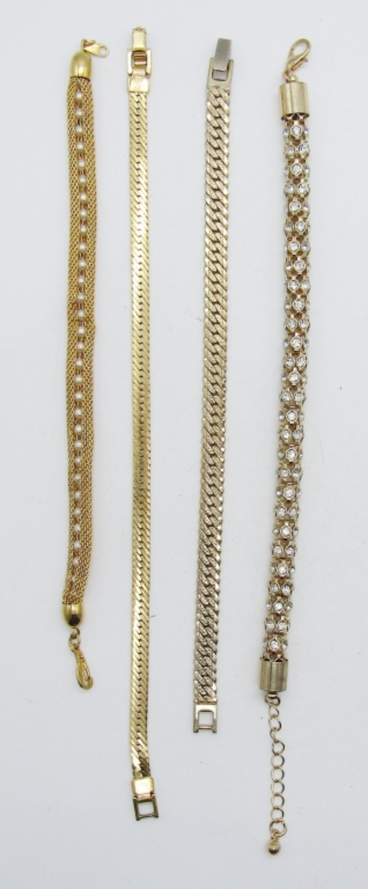 (4)GOLD TONE BRACELETS LOT: 2- SERPENTINE BRACELETS 7 1/2IN AND 9IN LONG, BOTH HAVE AN OPEN BOX CLASP, 1- 7 1/2IN LONG MESH CHAIN WRAPPED AROUND FAUX PEARLS, 1- 9IN LONG CLEAR RHINESTONES BRACELET, ADJUSTABLE.