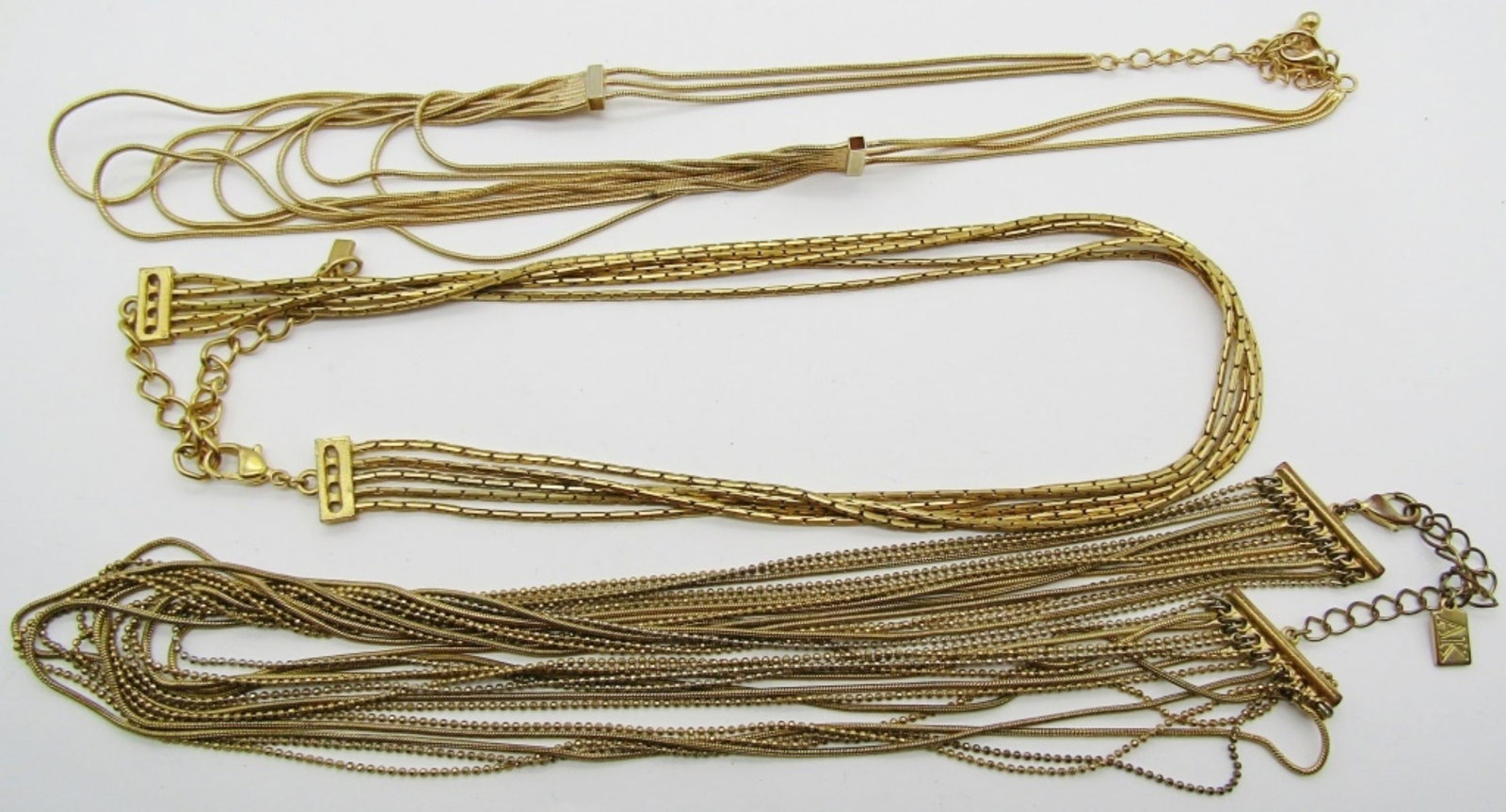 (3) GOLD TONE LAYERED CHOKERS: LENGTHS 17, 18, AND 19IN LONG, LOBSTER CLASP AND ALL ADJUSTABLE, 1 SNAKE STYLE CHAIN, 1 SNAKE AND BALL CHAIN, AND 1 BOX CHAIN