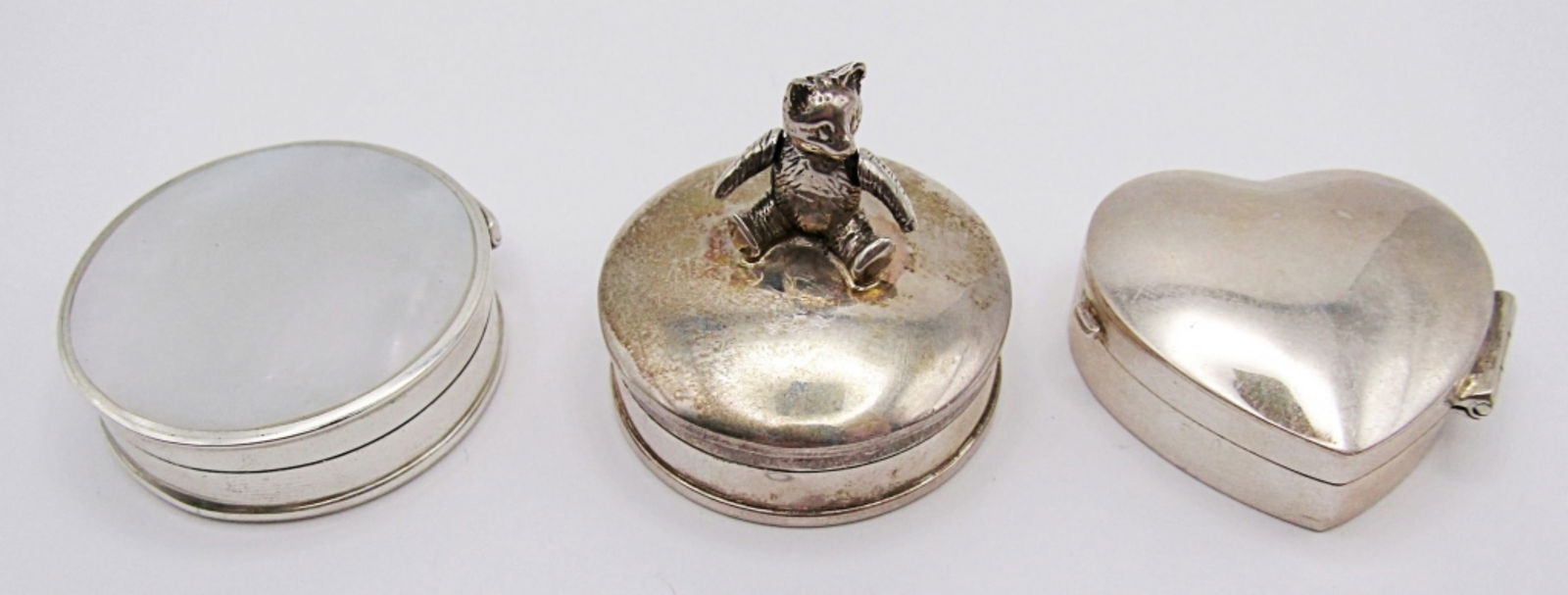 (3) HINGE STERLING PILL BOXES: 27DWT, ALL LITTLE OVER 1IN LONG. 1-HEART, 1- ABALONE INLAY CIRCLE, 1- CIRCLE WITH MOVABLE TEDDY BEAR ON TOP, ALL STAMPED ON THE BOTTOM 925