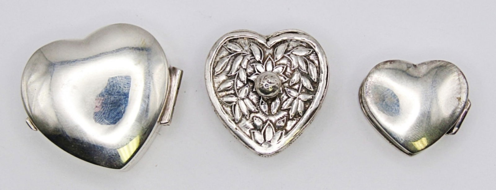 (3) MINI HEART STERLING PILL BOXES: 17.4DWT, BETWEEN 1IN TO LITTLE OVER AN IN, ALL STAMPED 925, THE ETCHED HEART HAS A POP-OFF TOP, 2 HAVE A HINGE TOP