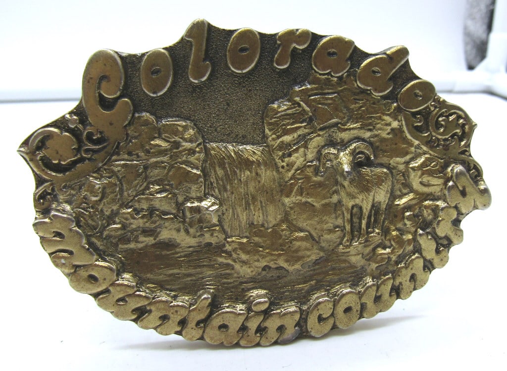 COLORADO MOUNTAIN COUNTRY BELT BUCKLE: GOLD TONE, ULTRA ENT. INC PENYER COLO. @COPY RIGHT 1980 STAMPED ON THE BACK, ALSO CARVED BY PAULA FREED