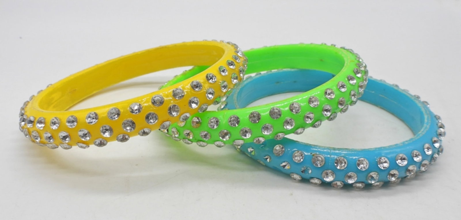(3) RHINESTONE STUDDED BANGLE SET: ALL 2.5" DIAMETER. BLUE, GREEN & YELLOW. SOME MISSING RHINESTONES