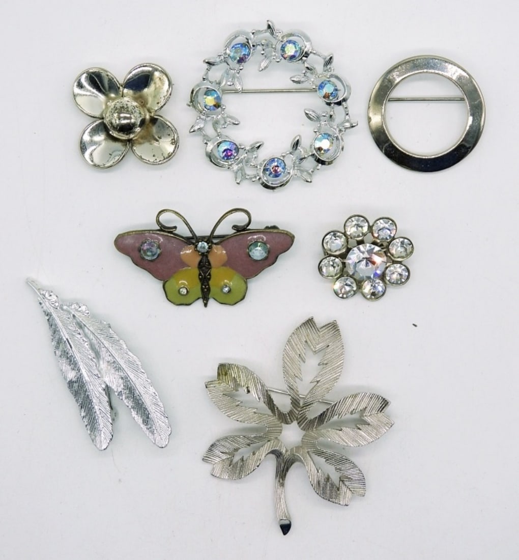 (7) Silver tone Brooches: Seven silver tone brooches with rhinestones and enamel. Largest measures 2"x2".