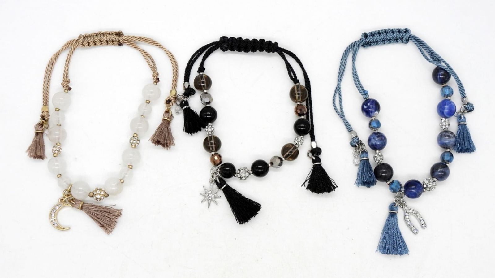 (3) BEADED TASSLE & CHARM BRACELETS: ADJUSTABLE CORD 1.5"-3.5" DIAMETER. BLUE HORSESHOE CHARM, BLACK STAR CHARM, & GOLD MOON CHARM.