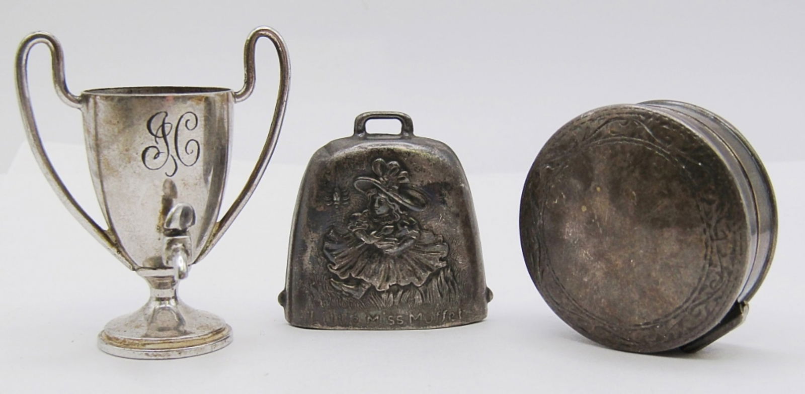 (3) STERLING SILVER TRINKETS: 24 DWT. PILL BOX STAMPED 925, LITTLE MISS MUFFET BELL & "JC" TROPHY BOTH STAMPED STERLING.