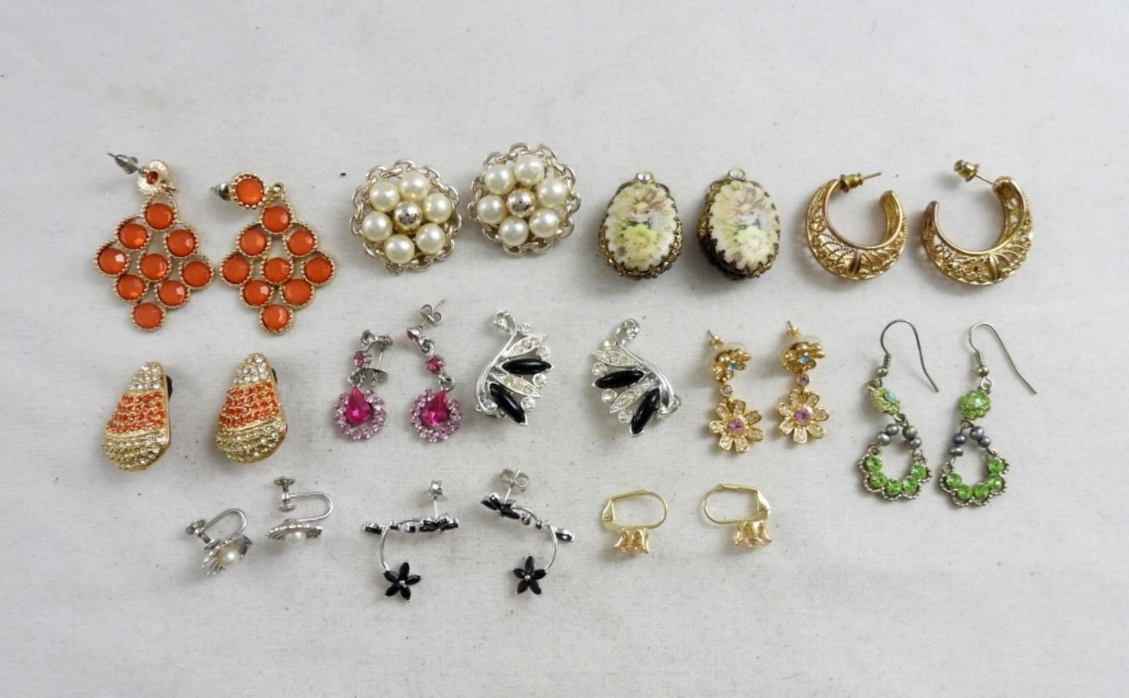 (12) FASHION EARRING LOT: 12 PAIRS OF RHINESTONE EARRINGS, THE COLORS VARY, SOME ARE THE CLIP-ON STYLE. 5 PAIRS THAT HAVE STUD BACKS WITH DROP STYLE PENDANTS. ALL IN GOOD CONDITION.