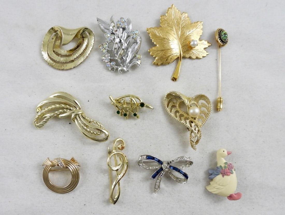 (11) VTG BROOCHES: GOLD & SILVER TONE BROOCHES, DUCK BROOCH, LEAF WITH A FAUX PEARL BROOCH, MUSIC SIGN BROOCH, BOW BROOCH (IS MISSING A COUPLE OF RHINESTONES). ALL IN GOOD CONDITION.