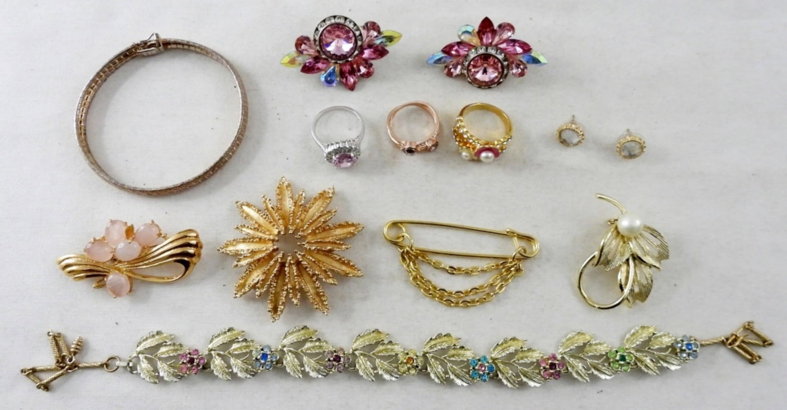 (11) PINK FASHION JEWELRY: STUNNING PINK RHINESTONE STUD POST WITH CLIP BACK, 4 GOLD TONE BROOCHES, 1- FLORAL BRACELET WITH FLOWERS & RHINESTONES, 1- PAIR OF GOLD TONE STUDS WITH CLEAR RHINESTONES, 1 GOLD TONE BRACELET, 3- RING