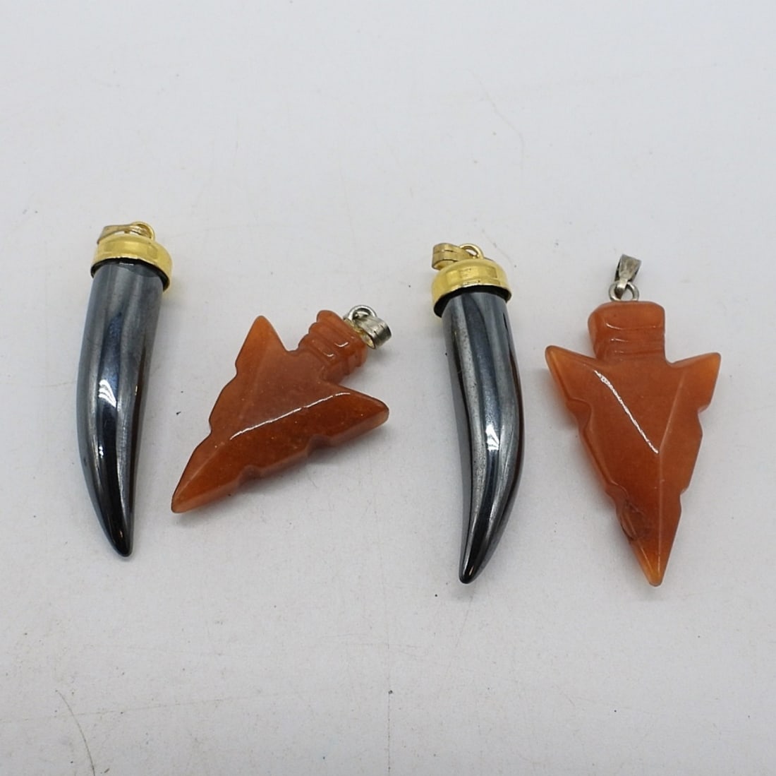 GOLDSTONE & HEMATITE PENDANTS: TWO GOLDSTONE ARROW HEAD PENDANTS. TWO TOOTH SHAPED HEMATITE PENDANTS. 1.5"
