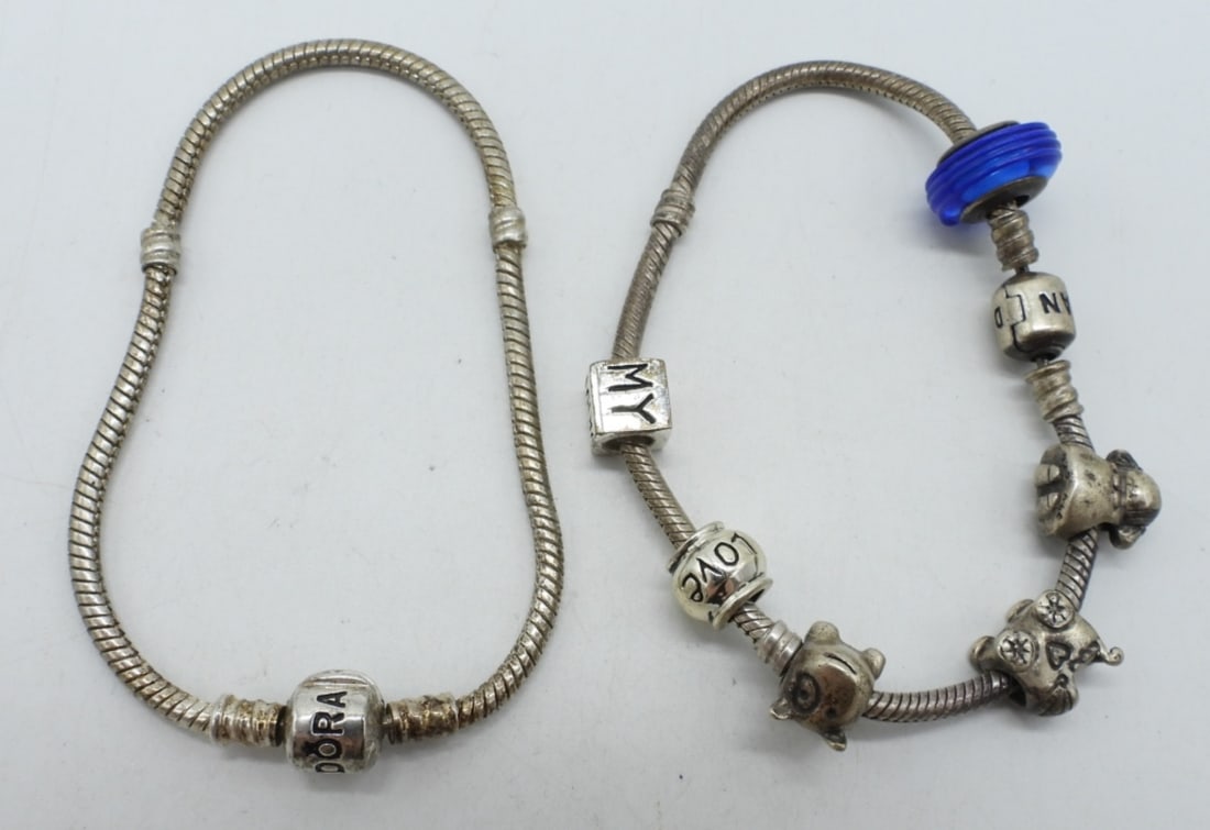 (2) PANDORA 925 BRACELETS W. CHARMS: TWO STERLING PANDORA CHARM BRACELETS, 6 STERLING CHARMS. (29.8 DWT)