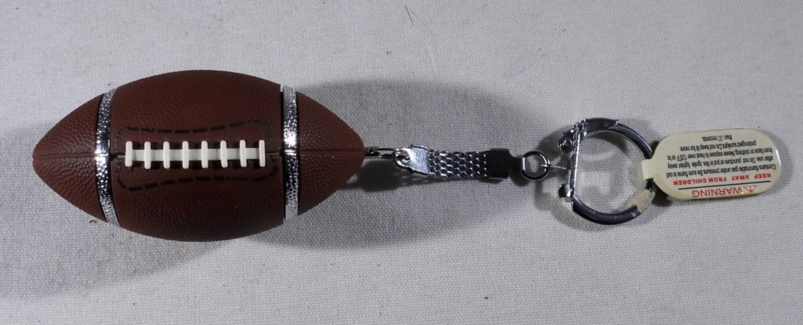 VTG FOOTBALL LIGHTER KEYCHAIN: VINTAGE 2003 FOOTBALL LIGHTER KEYCHAIN WITH TAG STILL ATTACHED. FIRED, HOLDS A NICE FLAME. FOOTBALL & KEYCHAIN MEASURE 5".