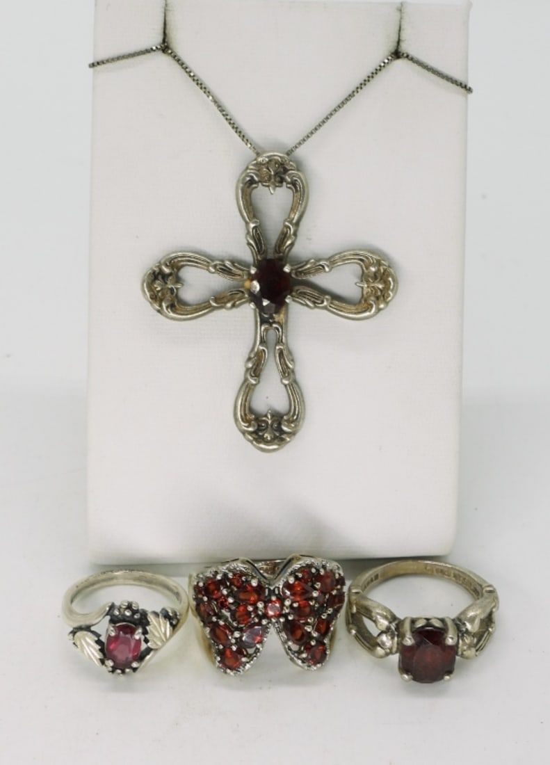 Garnet Sterling Rings and Cross Necklace: Three sterling rings with garnet gemstones, sizes 6, 7, 8. Sterling cross pendant, 2" long with a center garnet gemstone, on a 20" chain. (17 dwt) (6x4x2)