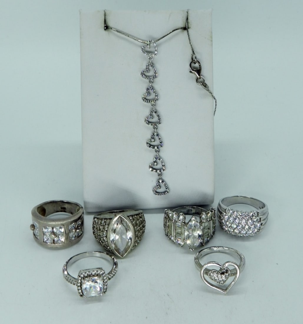7 Sterling Simulated Diamond Rings & More: Six sterling rings with simulated diamond gemstones. Sizes 6-9. Three inch long sterling heart pendant on a 16" sterling chain. (21 dwt)