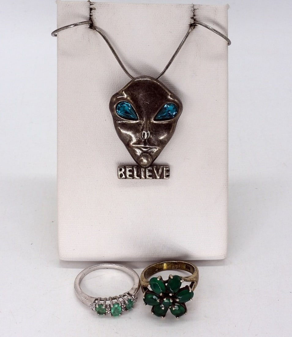 Sterling Alien Necklace & Green Rings: Sterling Alien "Believe" pendant ( and pin) with green gemstone eyes, 1.5" tall. On a sterling 20" chain. Two sterling rings with green gemstones, sizes 6 & 8. (12 dwt)