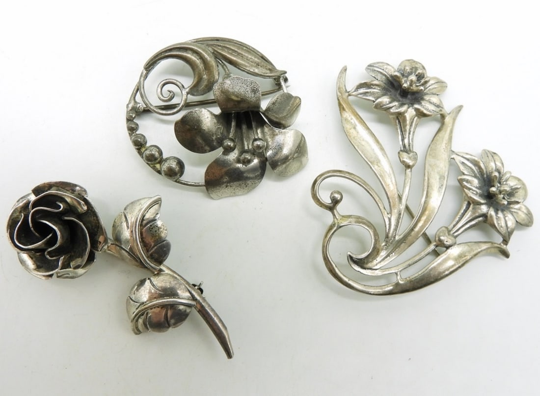 3 Vintage Sterling Flower Brooches: Three sterling flower brooches. Round brooch has a broken clasp. 1.5-2.5". (23 dwt)