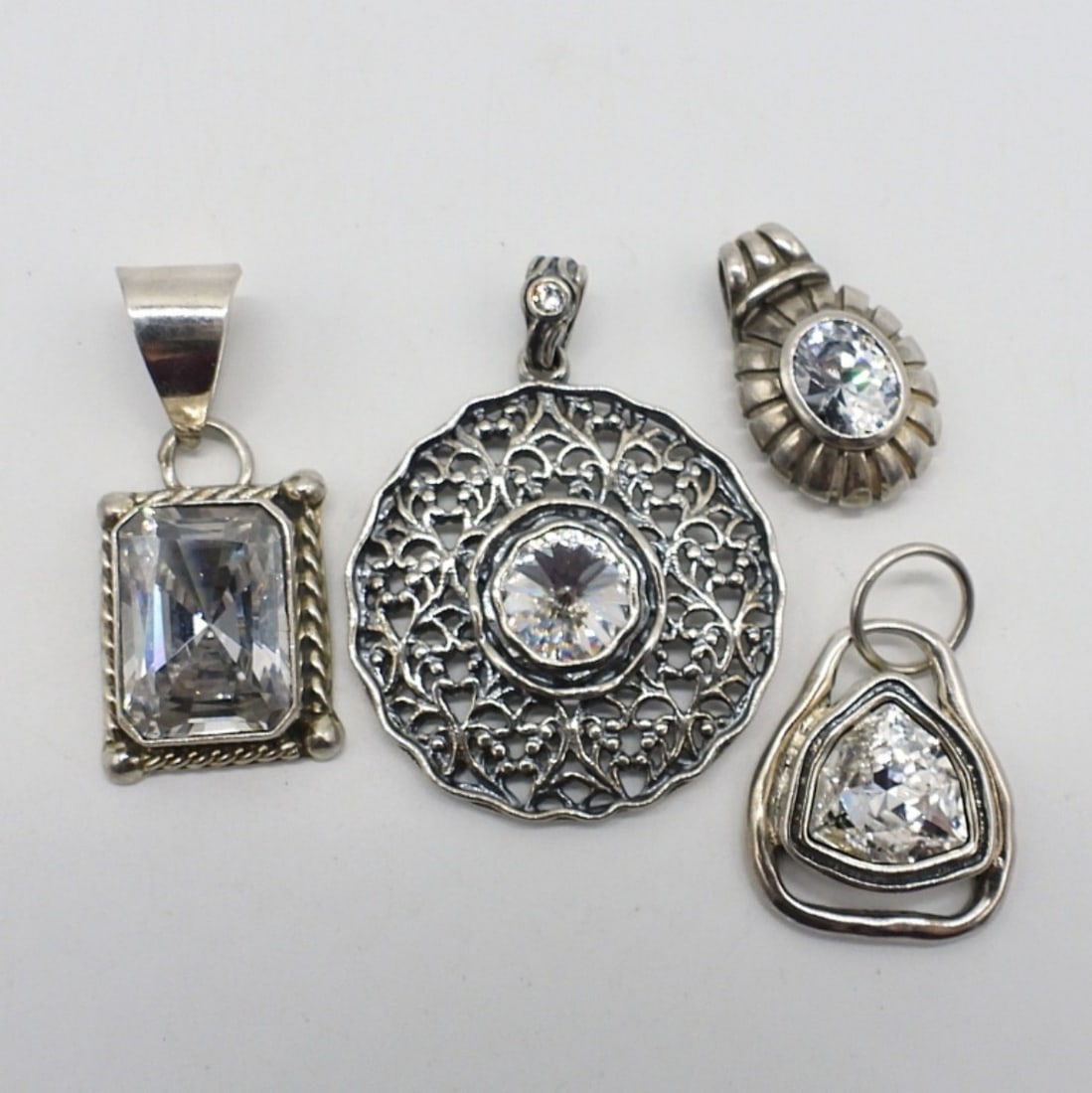 4 Sterling Simulated Diamond Pendants: Four sterling simulated diamond pendants, 1" - 2" long. (19.9 dwt)